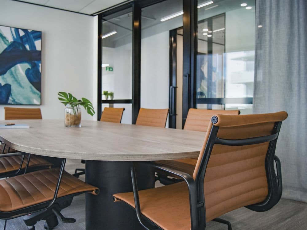 A meeting room with a wooden table, leather chairs and glass walls.