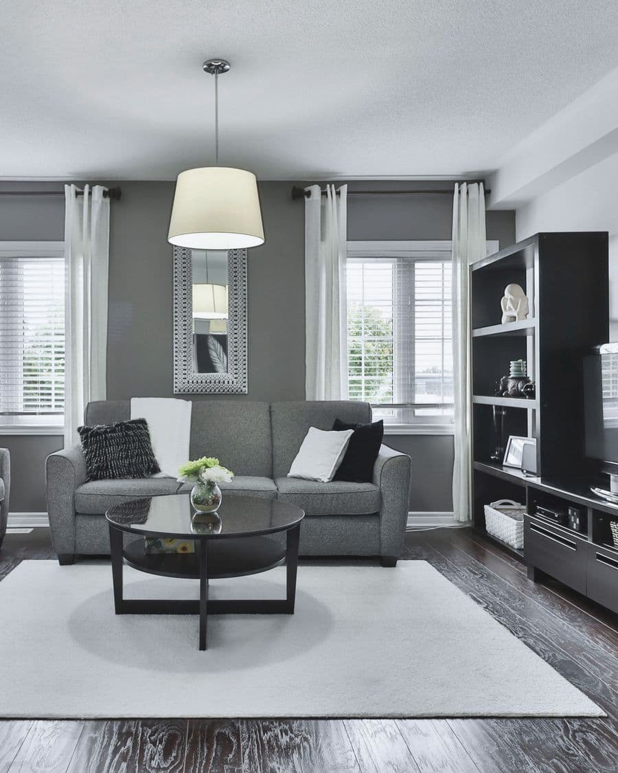 A sitting room with a grey sofa, a round coffee table and tall windows.